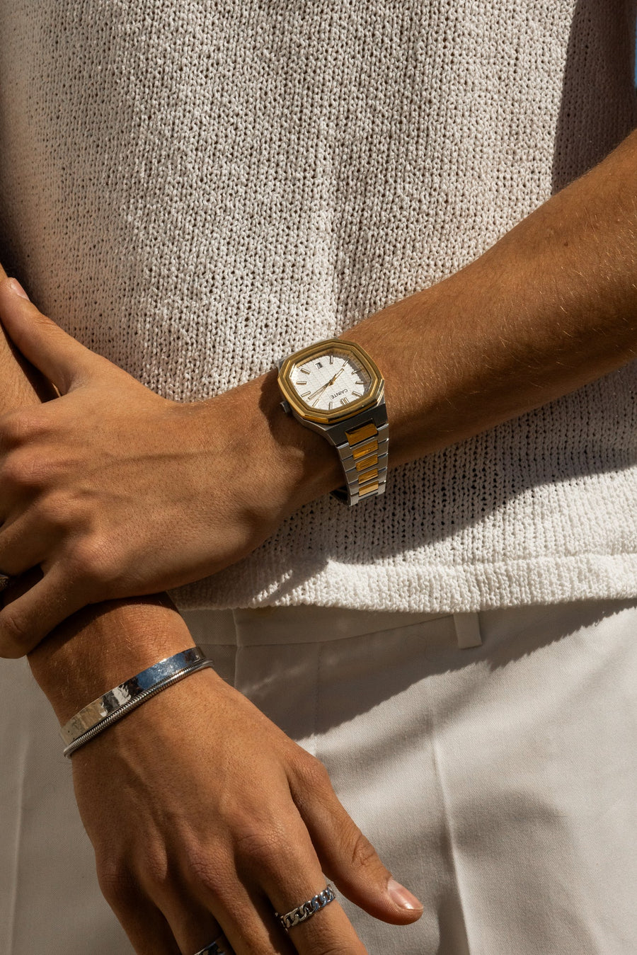 Arms crossed over a knit top, watch on the wrist