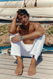 Man sitting on deck under the sail wearing the watch