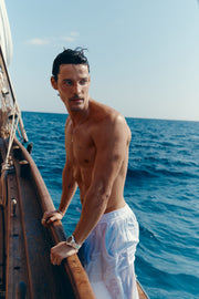 Man in a linen shirt leaning on a boat rail wearing the watch