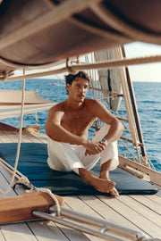 Man sitting on a boat deck wearing the automatic watch, wide shot