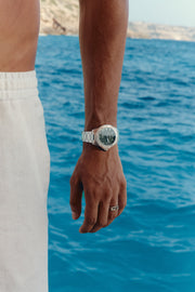 Watch with green dial worn on the wrist above the sea