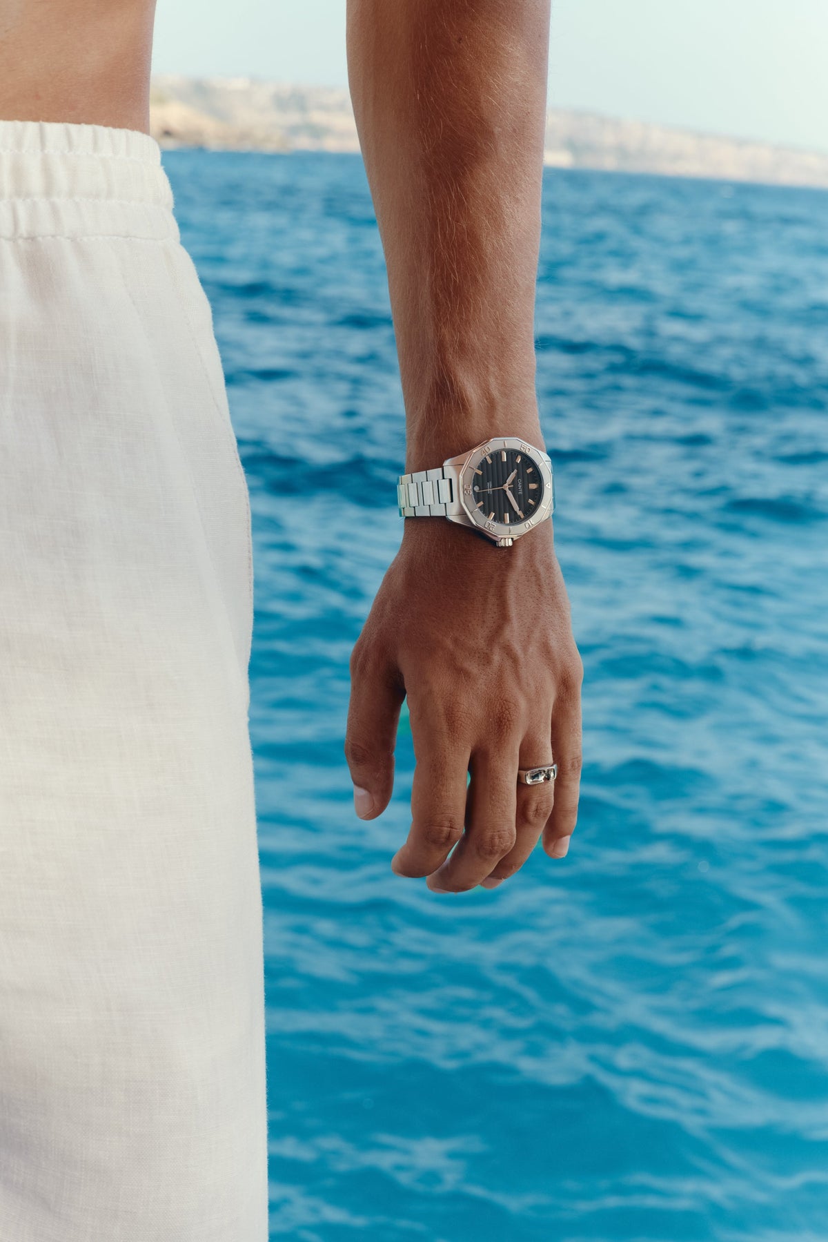 Watch with black dial worn on the wrist above the sea