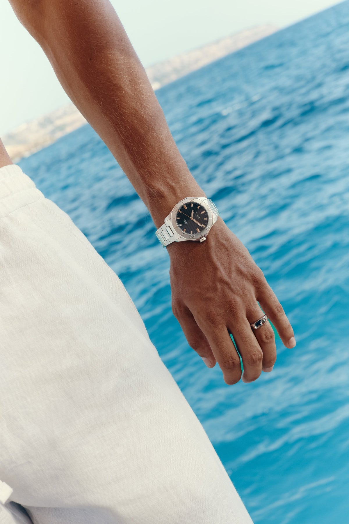 Close-up of the watch on the wrist, sea in the background