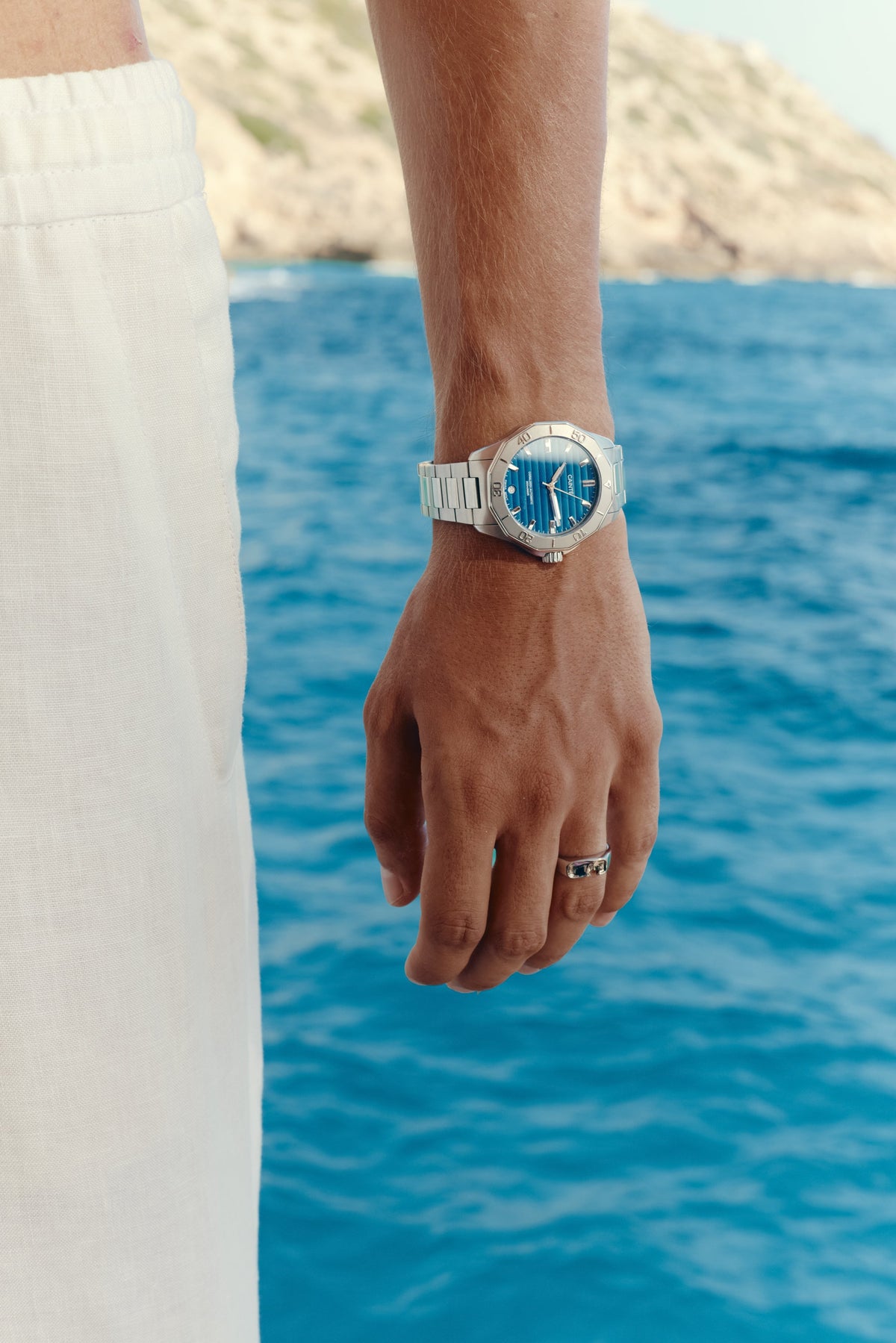 Watch with blue dial worn on the wrist above the sea