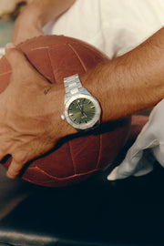 Close-up of the automatic watch on the wrist next to a leather ball