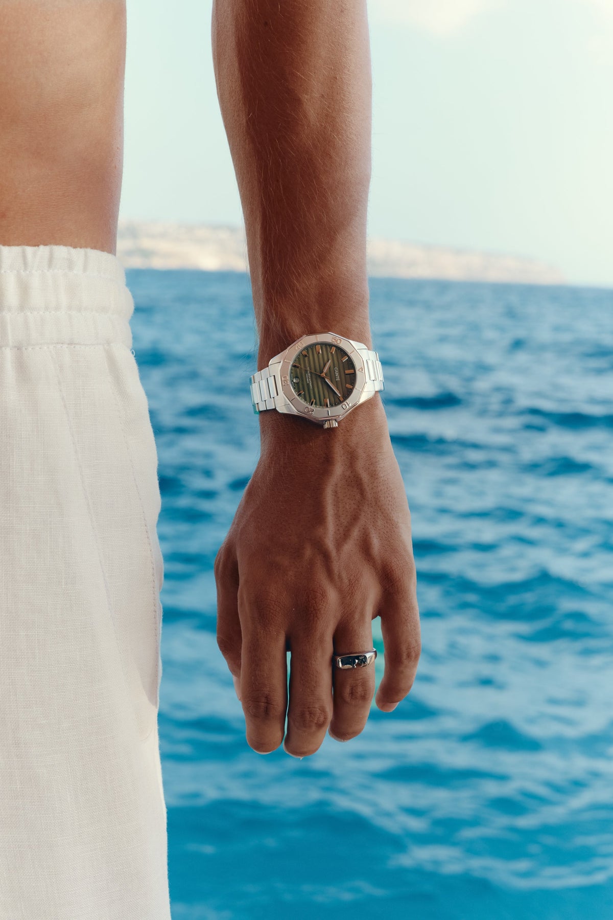 Green-dial automatic watch on the wrist against the sea