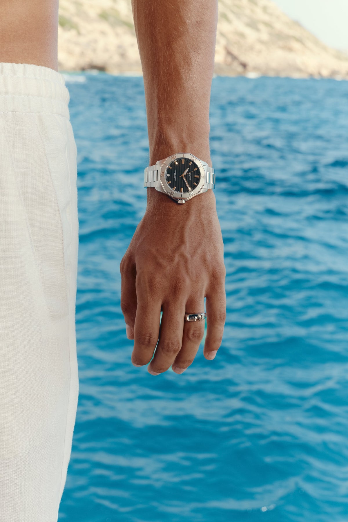 Watch with black dial worn on the wrist above the sea