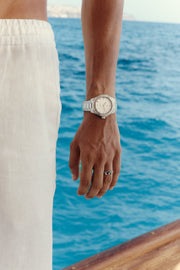 Hand by the water wearing the white-dial watch