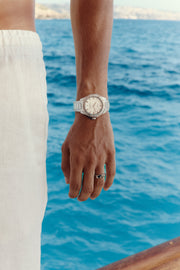 Watch with white dial worn on the wrist above the sea