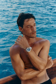 Arm across the chest showing the watch by the sea