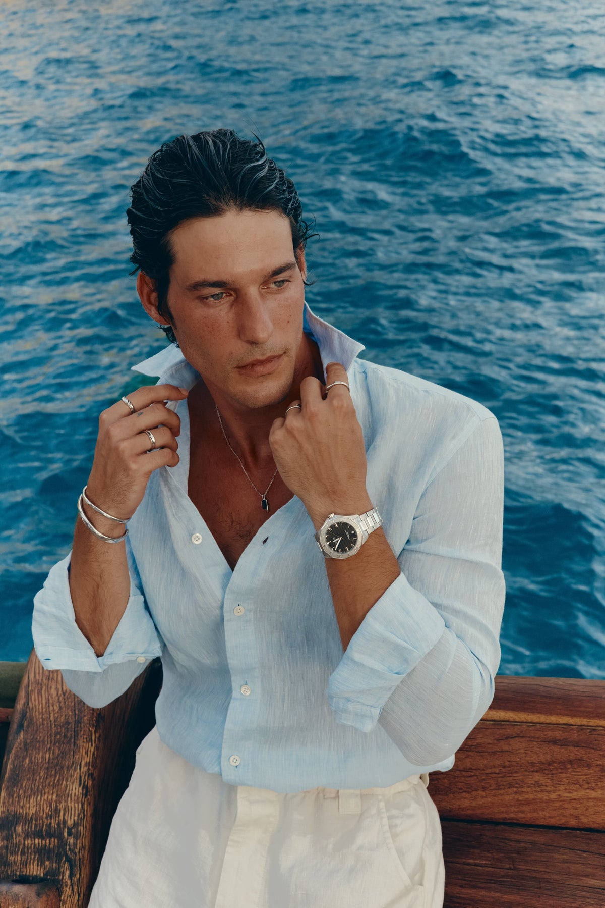 Man adjusting his collar on deck, watch on the left wrist