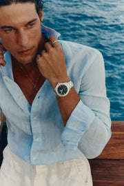 Man adjusting his collar on deck, watch on the left wrist