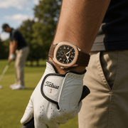 Rose gold-tone and brown watch worn on the wrist on a golf course