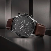 Gunmetal chronograph on a dark shelf, angled view