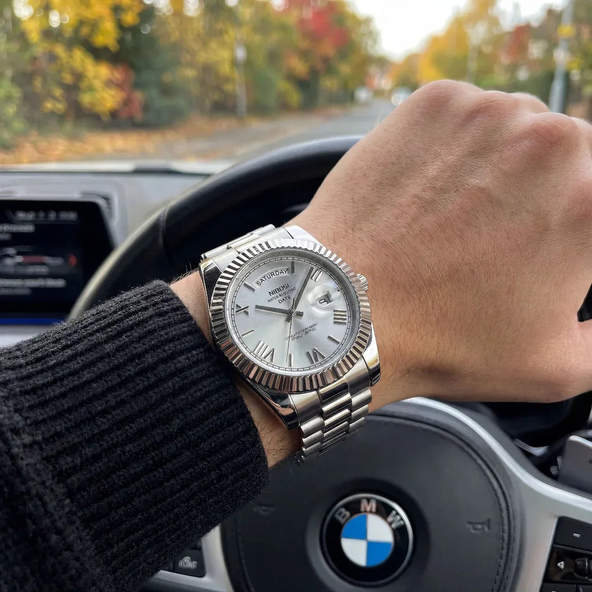 Silver dial watch on a wrist in a car