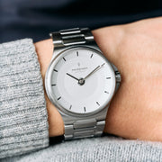 The watch worn on a wrist with a gray knit sweater sleeve.