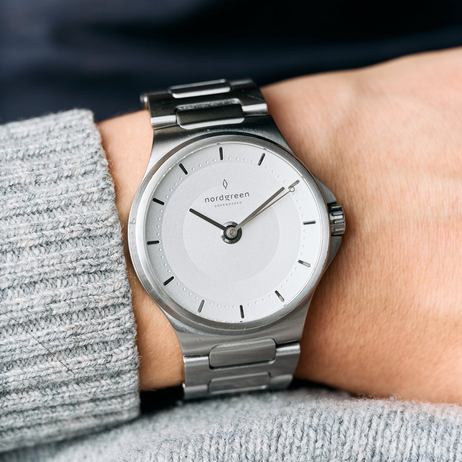 The watch worn on a wrist with a gray knit sweater sleeve.