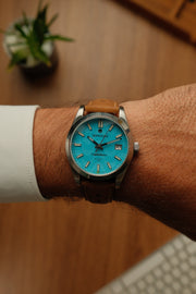 Turquoise watch on the wrist with a tan strap