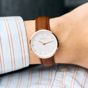 The watch worn on a wrist with a striped shirt cuff.