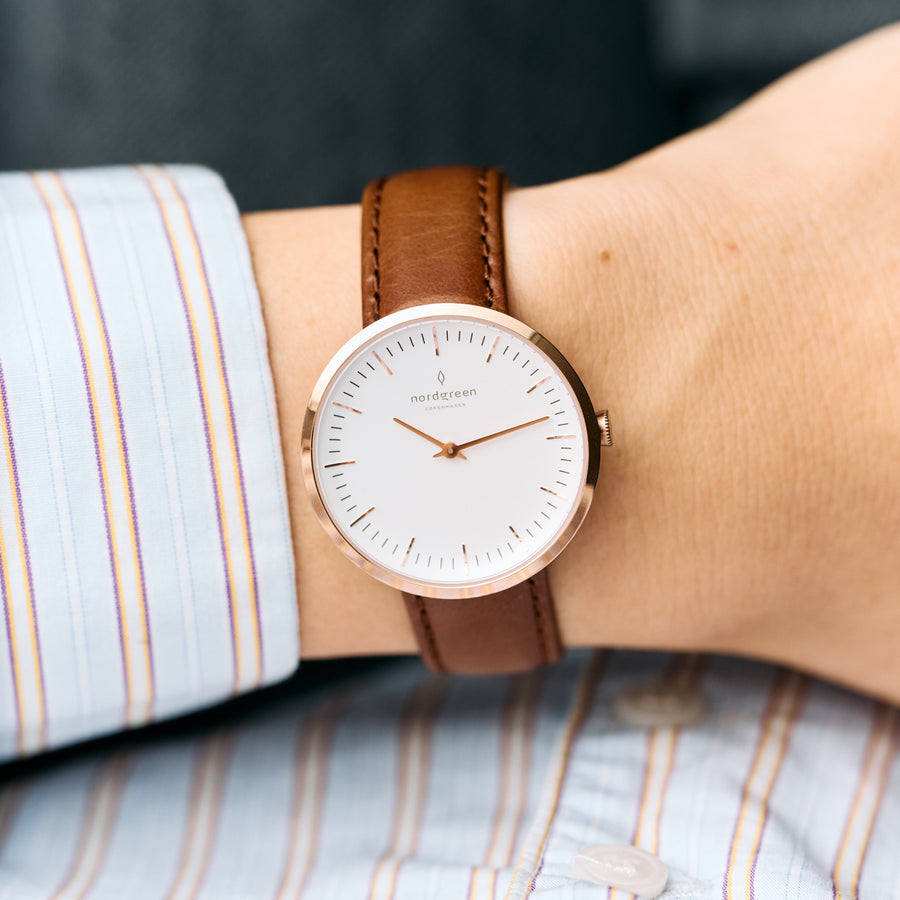 The watch worn on a wrist with a striped shirt cuff.