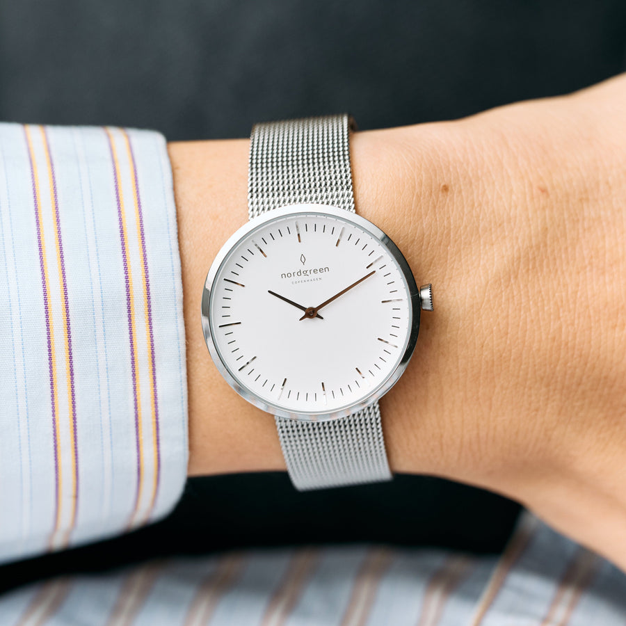 The watch worn on a wrist with a striped shirt cuff.