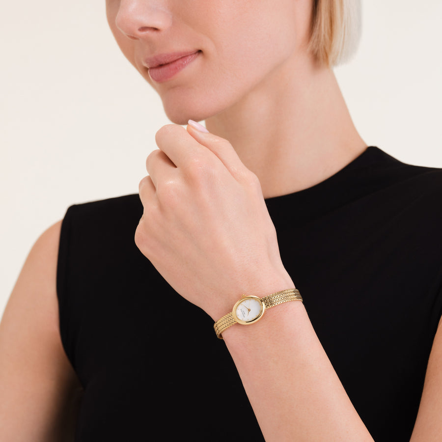 Oval watch on a wrist raised to the chin