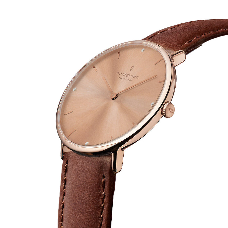 Angled view of the slim rose gold-tone case and crown with a brown strap.