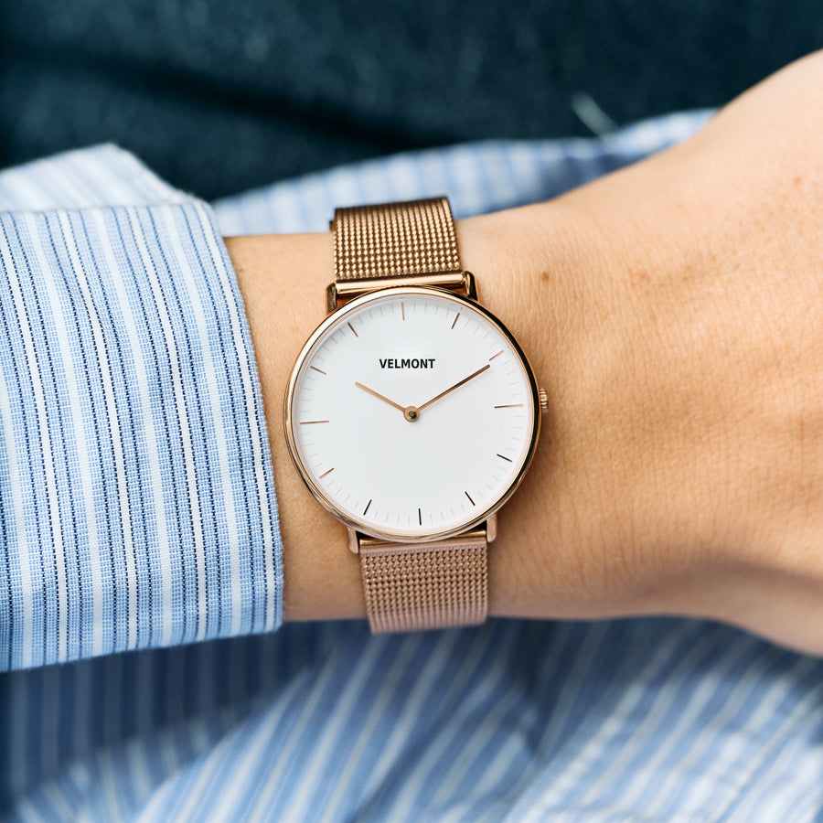 Worn on a wrist with a striped shirt, rose gold-tone mesh and white dial.