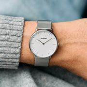 The mesh-strap watch worn with a gray ribbed sweater cuff.