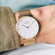 The gold-tone watch worn on a wrist with a khaki twill sleeve.