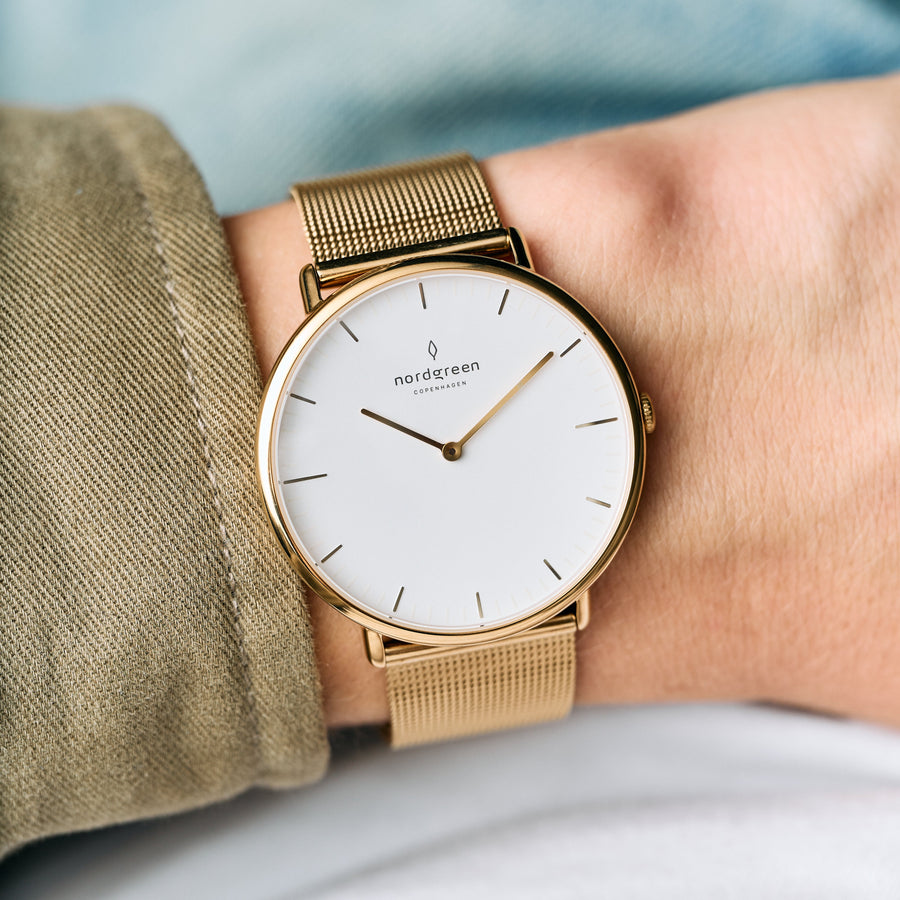 The gold-tone watch worn on a wrist with a khaki twill sleeve.