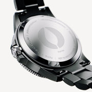 Engraved case back of the black watch with bracelet links attached.