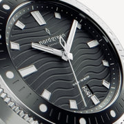 Macro view of the wave-pattern dial with white-filled hands and indices.