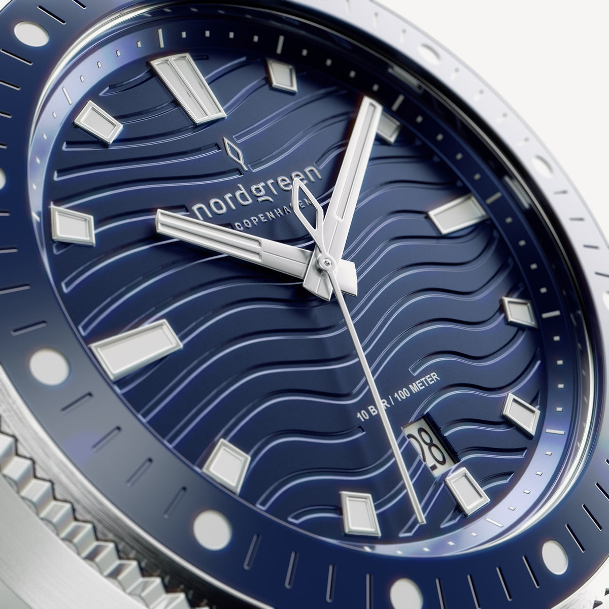 Close-up of the blue wave-textured dial with white-filled hands and indices.