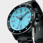Angled view of the turquoise dial and black coin-edge bezel with aqua dots.
