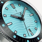 Close-up of the turquoise wave-textured dial and white-filled hands.