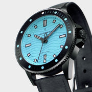 Angled view of the black case, crown and dotted bezel around the turquoise dial.