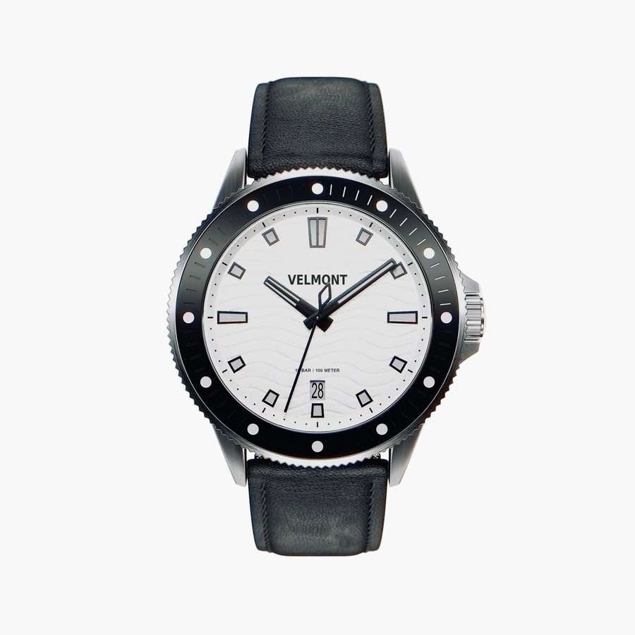 Diver-style watch with a white wave-textured dial and black bezel on a black strap.