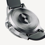 Silver-tone case back with a raised center medallion and dark strap.