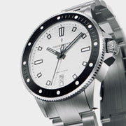 Three-quarter view of the white dial, black bezel and brushed bracelet.