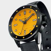 Angled view of the black case, crown and dotted bezel around the yellow dial.