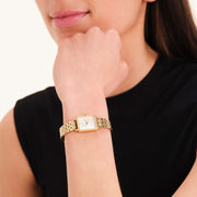 Gold-tone octagon watch on a wrist resting under the chin