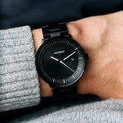 Black watch worn on a wrist with a gray knit sweater.