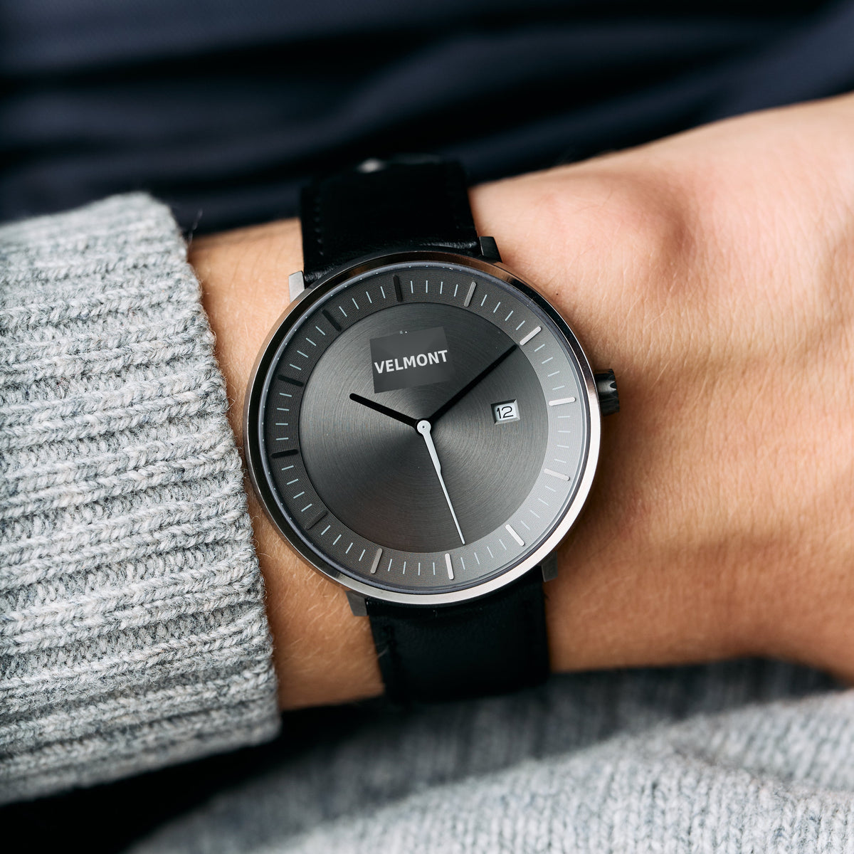 Worn with a gray knit sweater, the gunmetal watch shows its gray dial and black strap.