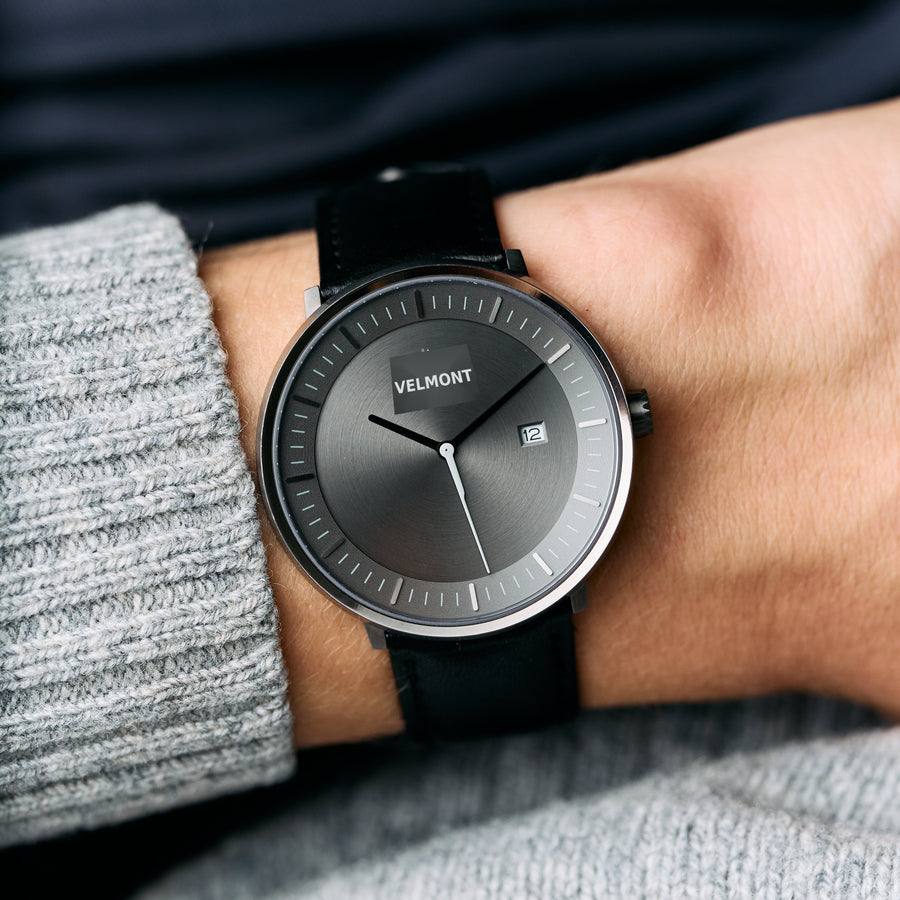 Worn with a gray knit sweater, the gunmetal watch shows its gray dial and black strap.