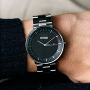 The black-dial watch worn with a dark navy knit sleeve.