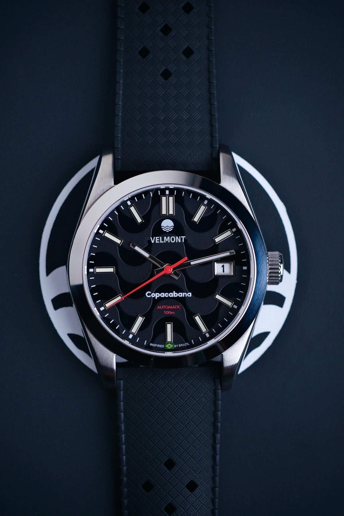 Black dial watch on a black strap against a blue background