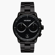 All-black chronograph-style watch with textured subdials on a black link bracelet.