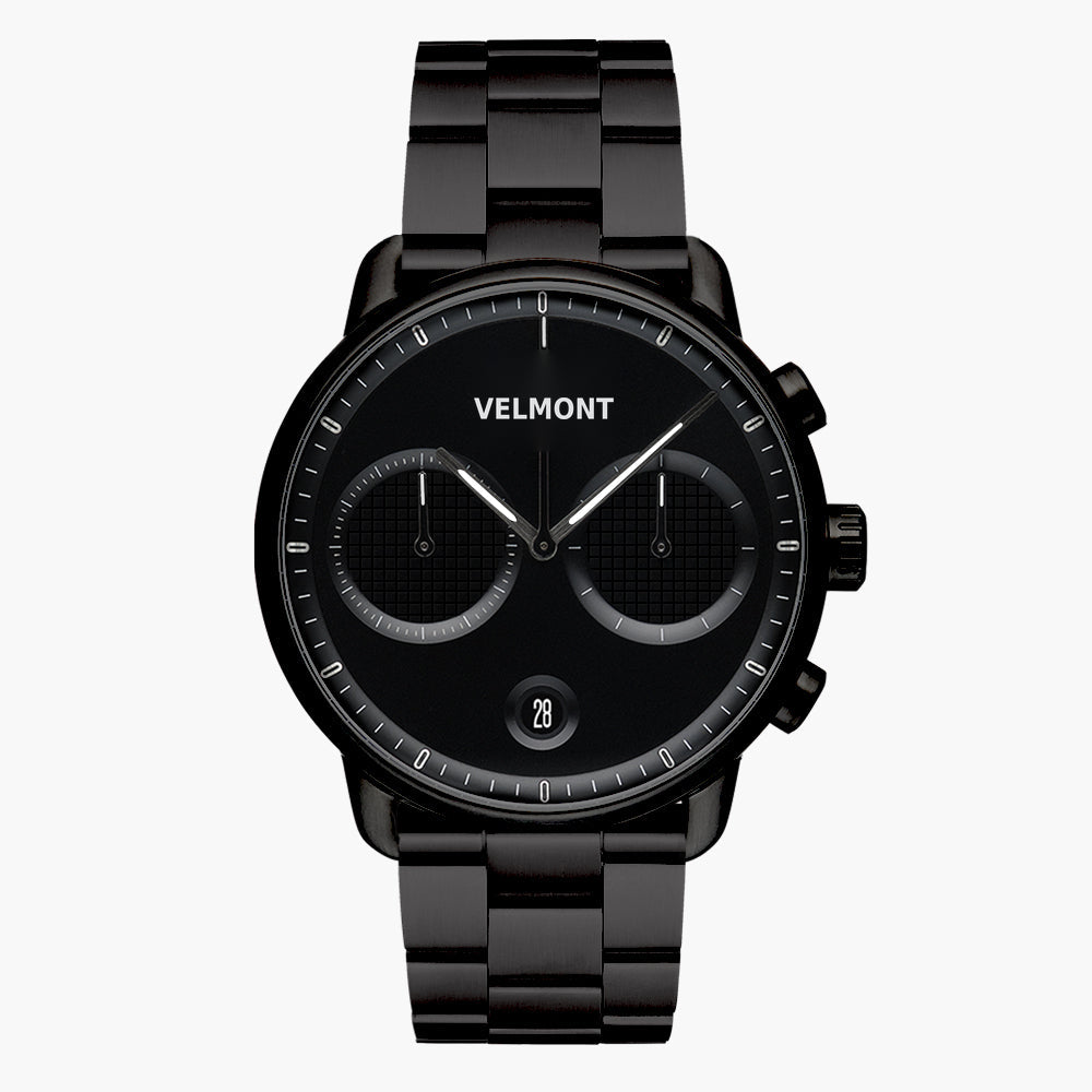 All-black chronograph-style watch with textured subdials on a black link bracelet.