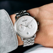 The silver-tone bracelet watch worn on a wrist next to a gray sweater.